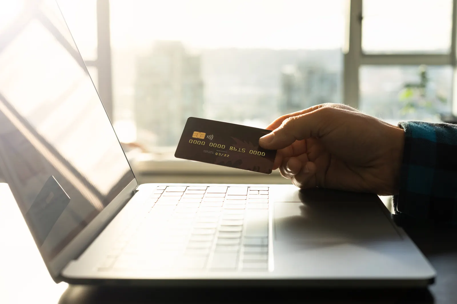 Hand using a payment card and laptop for an online purchase