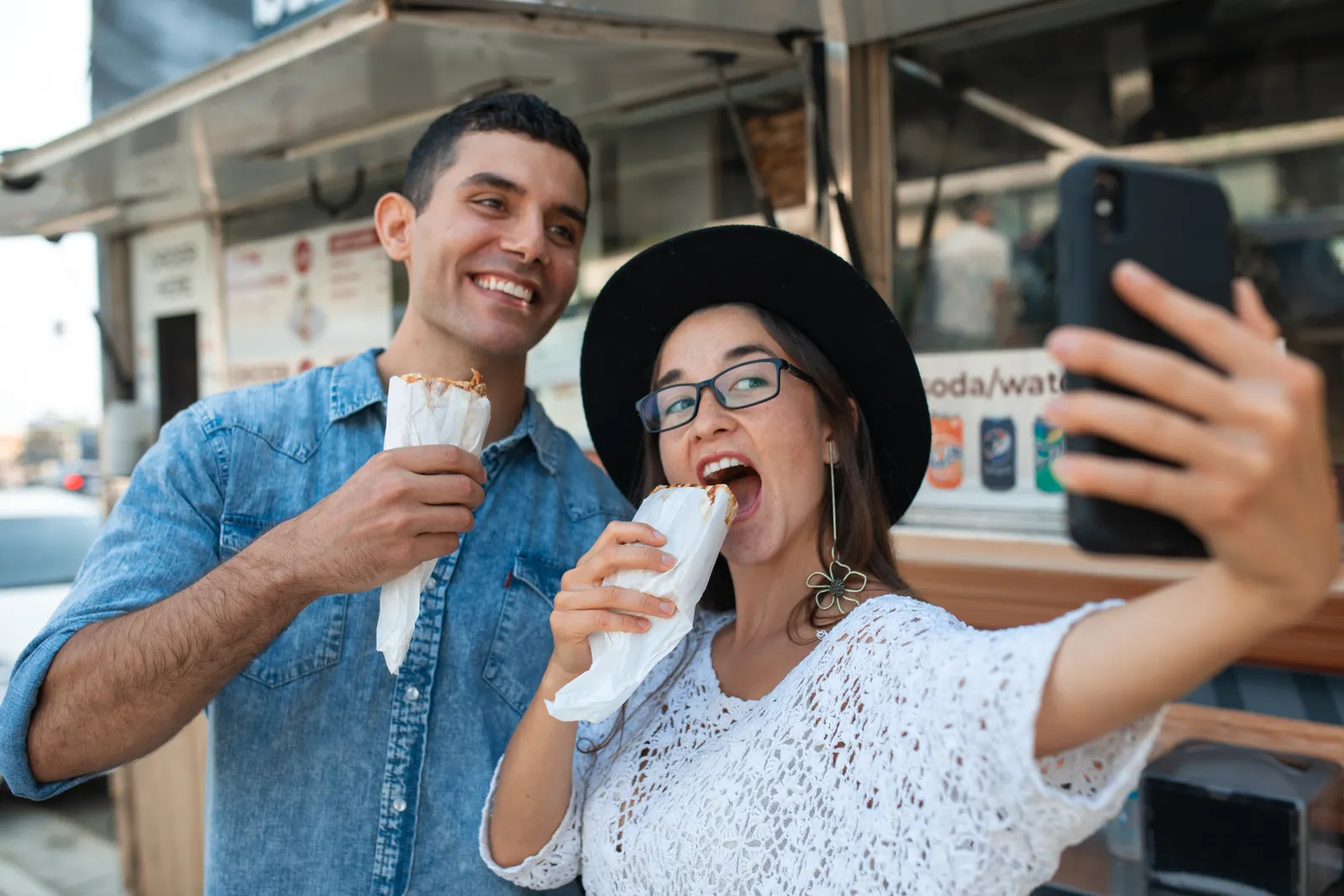 Friends enjoying street food while taking a photo outdoors